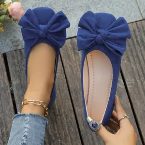 Dettaglio di eleganti ballerine in camoscio blu scuro con un grande fiocco decorativo