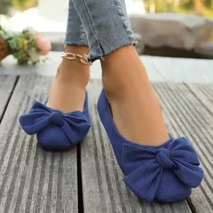Dettaglio ravvicinato di ballerine in camoscio blu con un grande fiocco decorativo