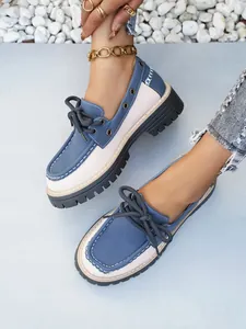 Detalle de mocasines de plataforma para mujer en azul y blanco con cordones estilo inglés.