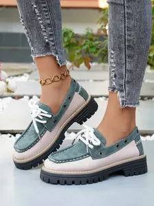 Primer plano de mocasines con plataforma bicolores para mujer con cordones blancos.