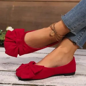 Primo piano dettagliato di ballerine in camoscio rosso con un grande fiocco chic.