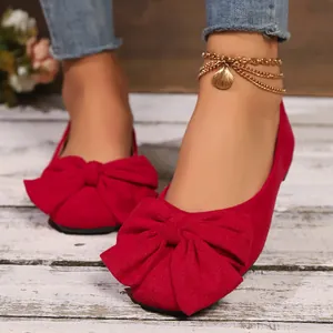 Primo piano di ballerine in camoscio rosso con un grande fiocco decorativo sulla punta