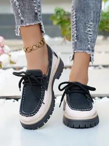 Primer plano de mocasines con plataforma bicolores de estilo británico y cordones