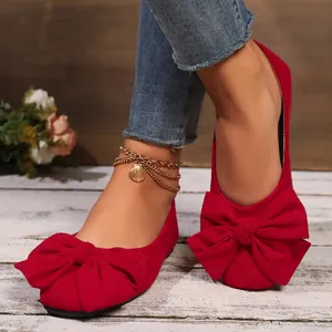 Dettaglio ravvicinato di ballerine in camoscio rosso con un vistoso fiocco decorativo