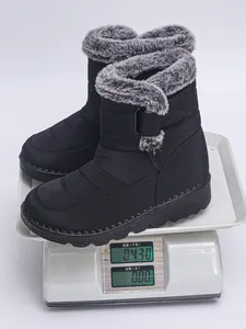 Weight detail of black waterproof winter snow boots with faux fur collar on scale