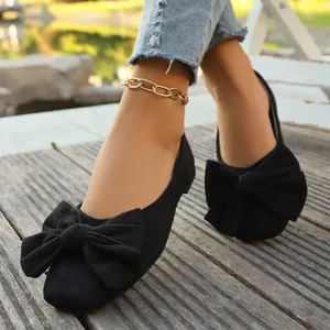 Dettaglio di eleganti ballerine in camoscio nero con un grande fiocco decorativo