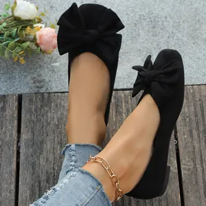 Vista dettagliata di scarpe basse in camoscio nero con grande fiocco decorativo