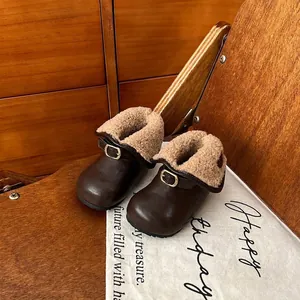 Gros plan de bottines en cuir marron pour fillettes avec doublure polaire et boucle.
