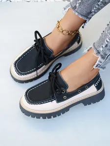 Vista detallada de mocasines de plataforma bicolor con cordones negros y costuras en contraste
