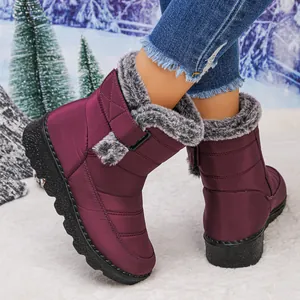 Close-up of wine red waterproof snow boots with fur lining and velcro strap on snow