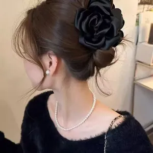 Close-up detail of large black satin rose hair clip styled in an elegant bun on the head.