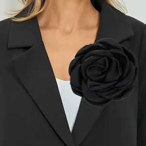 Grande spilla a camelia nera fatta a mano da 12 cm appuntata sul risvolto di un blazer