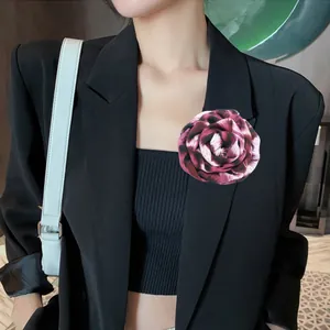 Primo piano di una spilla a forma di rosa leopardata vintage sul bavero di un blazer nero.