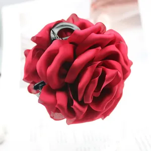 Close-up of a large red satin rose hair claw clip with elegant fabric petals