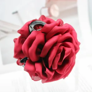 Macro view of a large dark red satin rose fabric hair claw clip for elegant styling