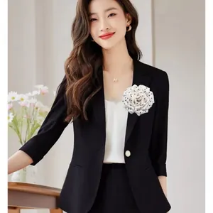 Detailed view of an elegant French style polka dot peony brooch on a black blazer.