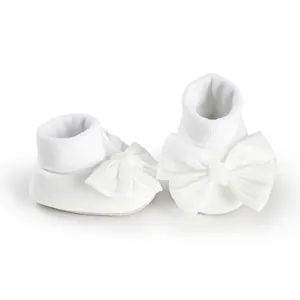 Elegant white baby bow walking socks with large satin ribbon detail on plain background