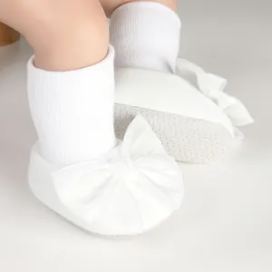 Detailed view of white baby walker socks featuring a large bow and anti-slip dotted sole