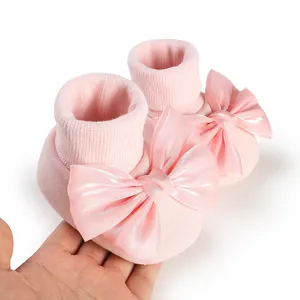 Detailed view of soft pink baby floor socks featuring a large satin bow held in hand