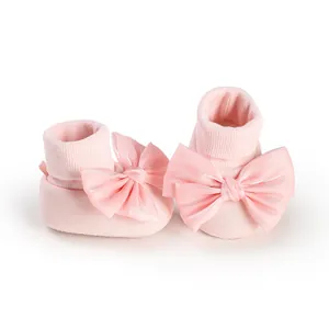 Close-up of pink baby floor socks featuring a large satin bow and soft knit texture