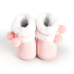 Close-up detail view of pink baby boots with white faux fur lining and pom-poms