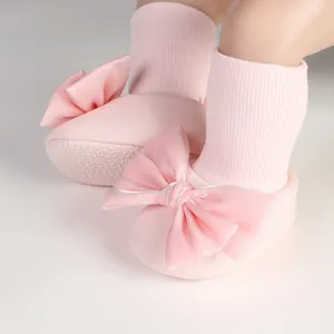 Detail of pink baby floor socks featuring a large decorative silk bow decoration.