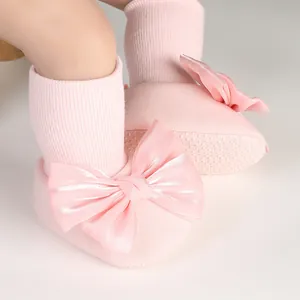 Detail of pink baby floor socks featuring a large satin bow and non-slip sole