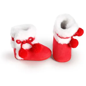 Close-up of red baby winter boots featuring white faux fur lining and cute pom-poms
