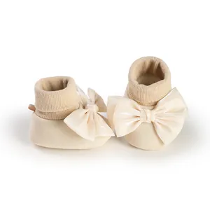 Close-up of cream baby walker socks featuring a large decorative bow