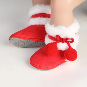 Close-up detail of red winter baby boots featuring soft white faux fur trim and cute pom-poms