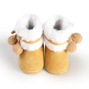 Warm yellow winter baby boots featuring plush white faux fur trim and decorative pom-poms.