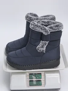 Detailed view showing the weight of navy blue waterproof snow boots on a digital scale.