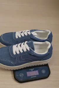 Detailweergave van blauwe denim sneakers op een digitale weegschaal met een gewicht van 409,7 g.