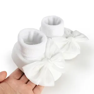 Pure white baby walking floor socks featuring large decorative satin bows for infant girls