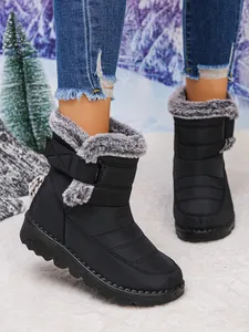 Close-up detail of black waterproof women's snow boots featuring faux fur trim and velcro strap