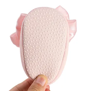 Close-up of pink baby shoe sole with non-slip rubber dots and satin bow detail