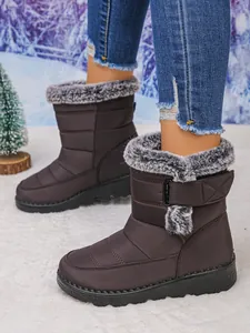Close-up of brown women's snow boots with grey faux fur trim and adjustable velcro strap