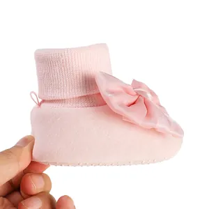 Close-up of pink baby winter shoe with large satin bow and soft knit cuff