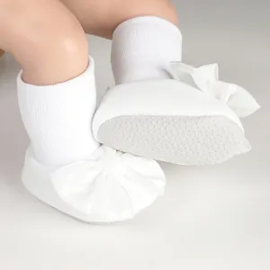 Detail view of white baby bow shoes with non-slip soles for newborns