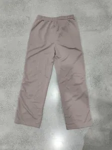 Rear view of heavyweight dusty rose straight-leg sweatpants on a textured grey floor