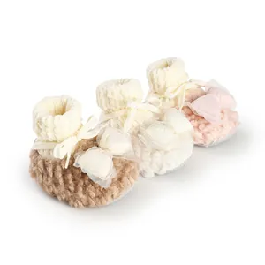 Three pairs of soft knit winter baby booties with decorative mesh bows in brown and pink