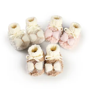 Detailed view of three pairs of plush winter baby booties in soft pink, cream, and brown