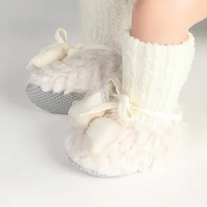 Close-up detail of warm fleece baby booties featuring knitted cuffs and mesh bows