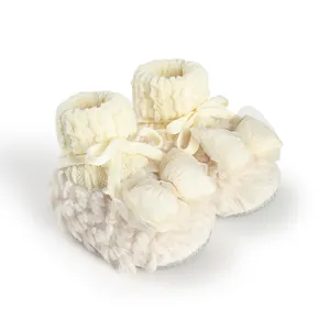Close-up detail of fuzzy baby winter booties with an elegant tulle bow and soft knit cuff