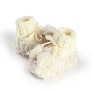Detailed view of soft plush cream baby booties featuring knitted cuffs and a delicate bow