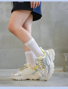 Primer plano de zapatillas chunky beige y plateadas usadas por un modelo en estudio.