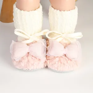 Close-up detail of fuzzy pink baby socks shoes with large decorative bows