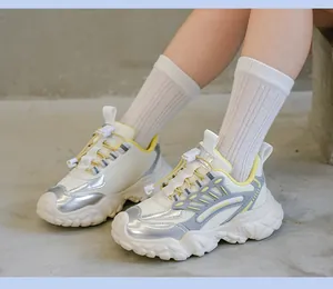 Detalle de zapatillas de cuero blanco con acentos plateados metalizados y ribete amarillo.