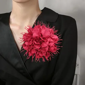 Detailweergave van een oversized fuchsia stoffen bloembroche van 18 cm op een zwarte blazer