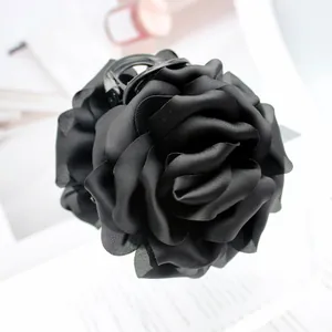 Detailed close-up of a large black satin rose hair claw clip with elegant fabric petals